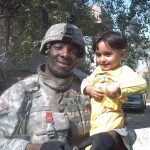 U.S. Army infantry squad leader Isiah James poses with a boy in Baghdad, Iraq, during his first deployment to the region between 2006 and 2008